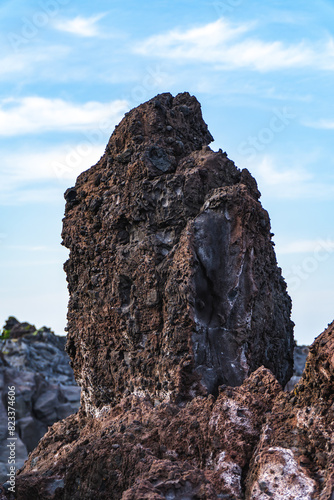 A beautiful coastal area in eastern part of Japan. A clear blue sky and an orange sunrise reflects on the sea water. A big rock formation in the coast line. Island from the distance.