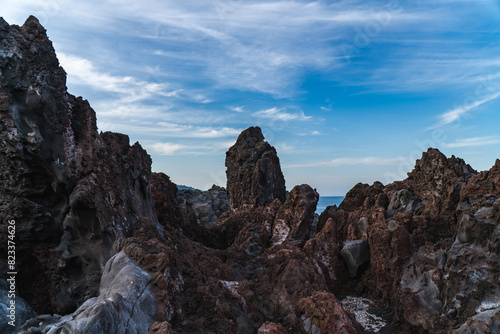A beautiful coastal area in eastern part of Japan. A clear blue sky and an orange sunrise reflects on the sea water. A big rock formation in the coast line. Island from the distance.