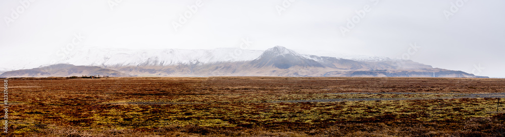 Fototapeta premium Vast field with snow-capped mountains in the background. Iceland