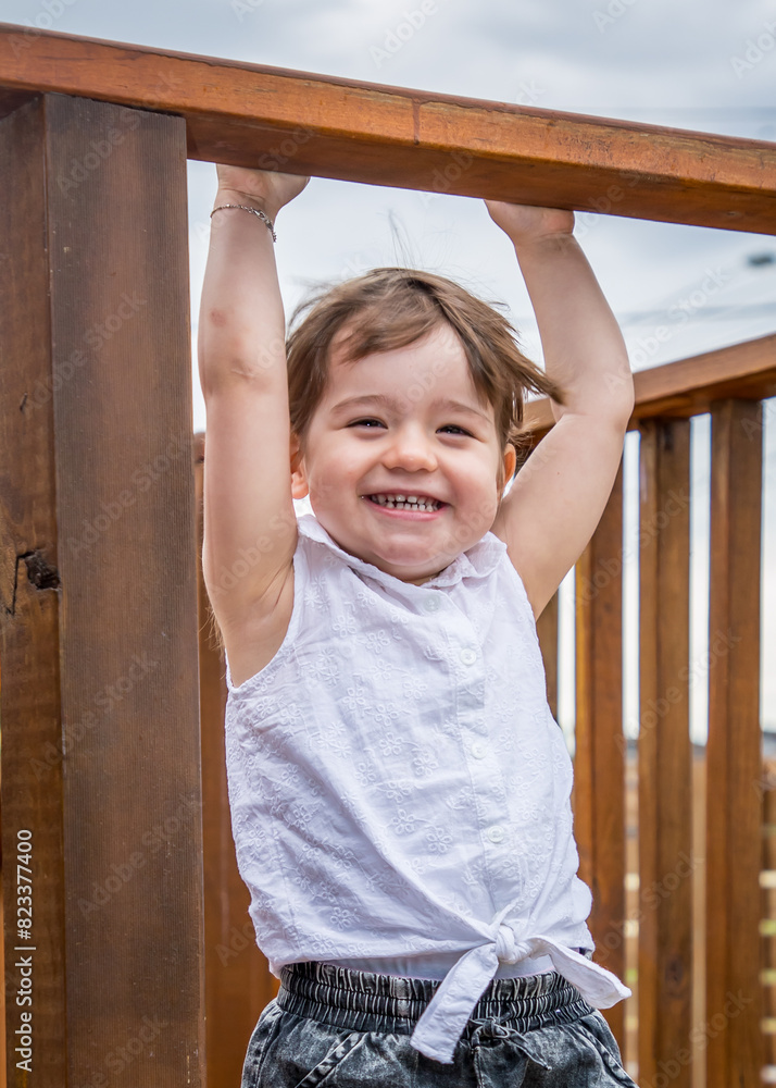 Obraz premium small toddler hanging upside down on a wooden ledge by itself