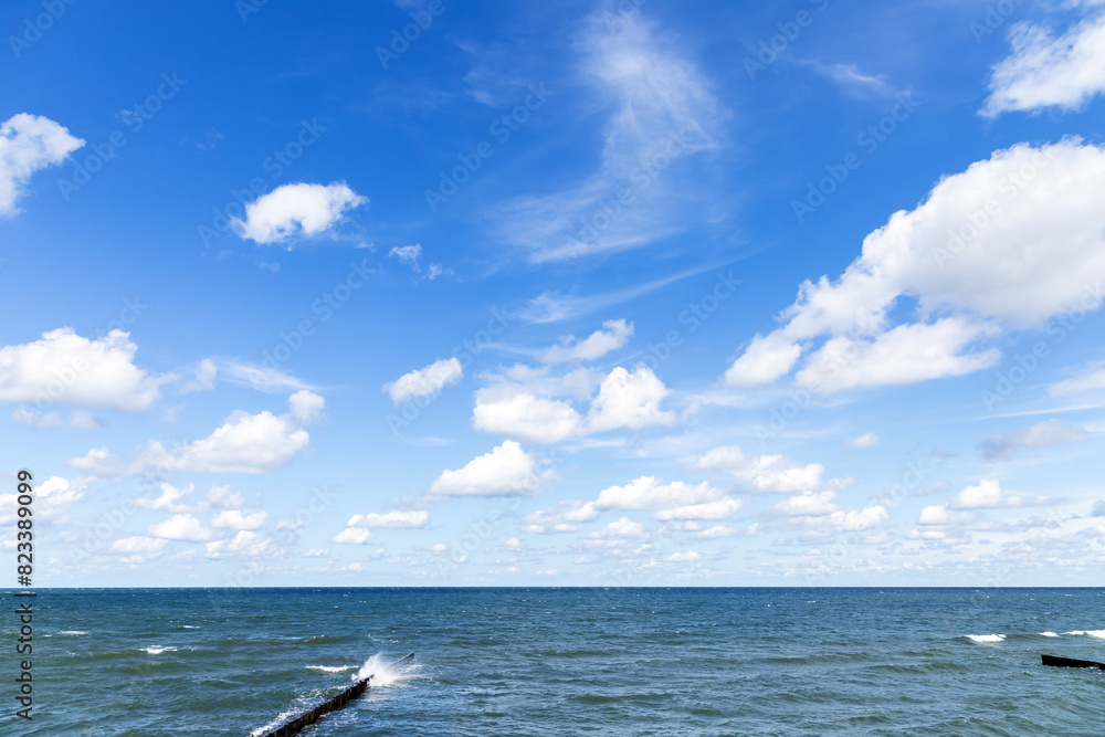 Fototapeta premium Baltic sea coastal view with breakwaters under cloudy blue sky