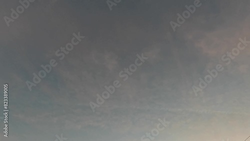 Timelapse low angle shot of an airplane with smoke tail flying over the dusk clouds at sunset photo
