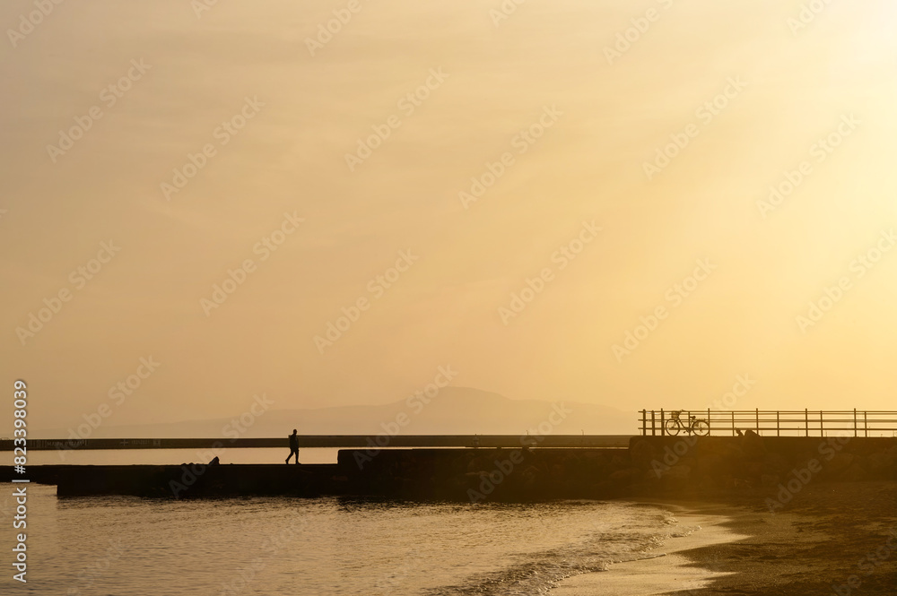 Silhouette of a man walking next to the sea during the sunset Silhouette of a man walking next to the sea during the sunset
