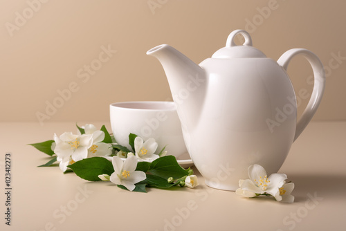A white tea cup and teapot with a jasmine flowers