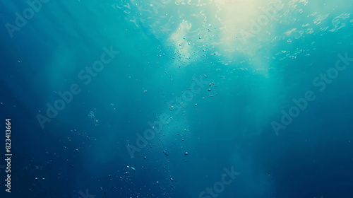 Underwater light rays and bubbles. Sunlight shining through the surface of a deep blue ocean with air bubbles rising to the top. © kosarit