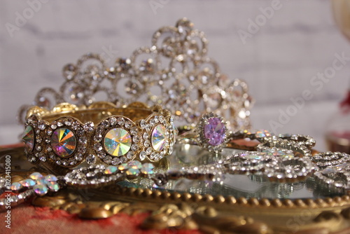 Crown and jewelry next to a mirror in an elegant display © Wirestock