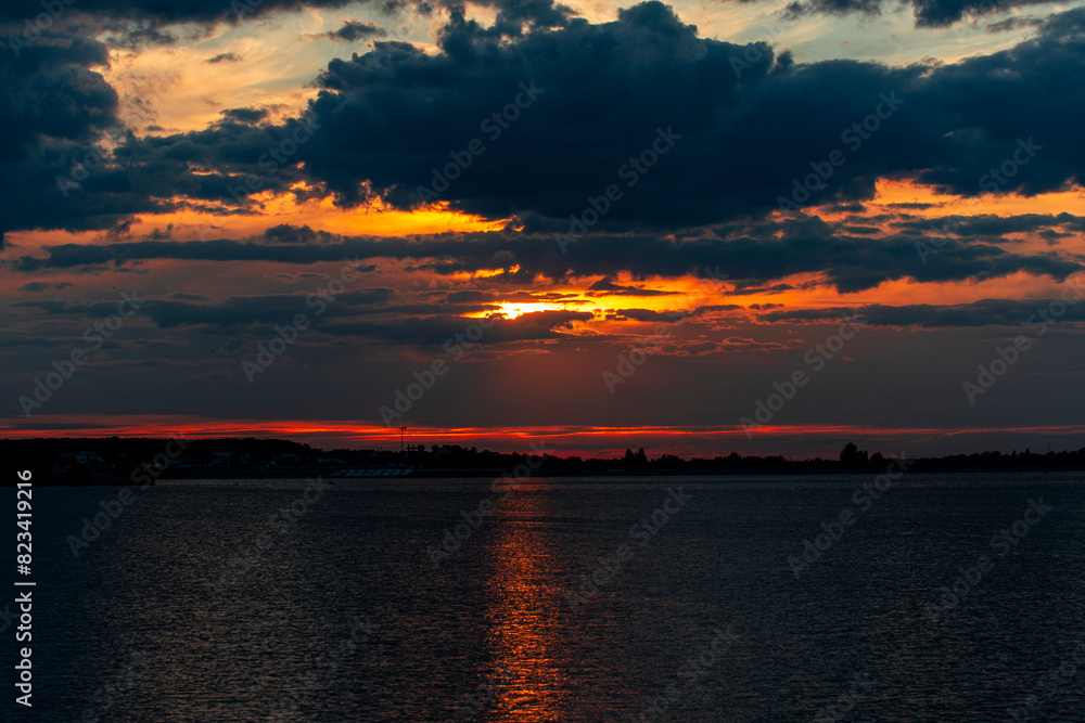 Fototapeta premium Dark, cloudy sunset casting a dramatic light on the sky