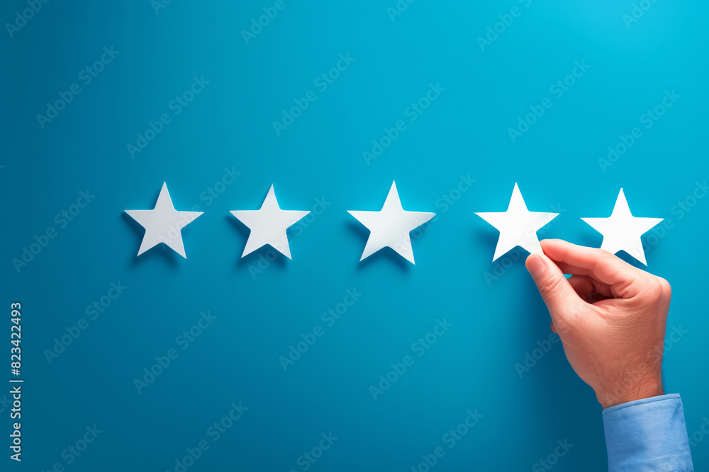 Five-star rating with a hand placing a star on a blue background Five-star rating with a hand placing a star on a blue background