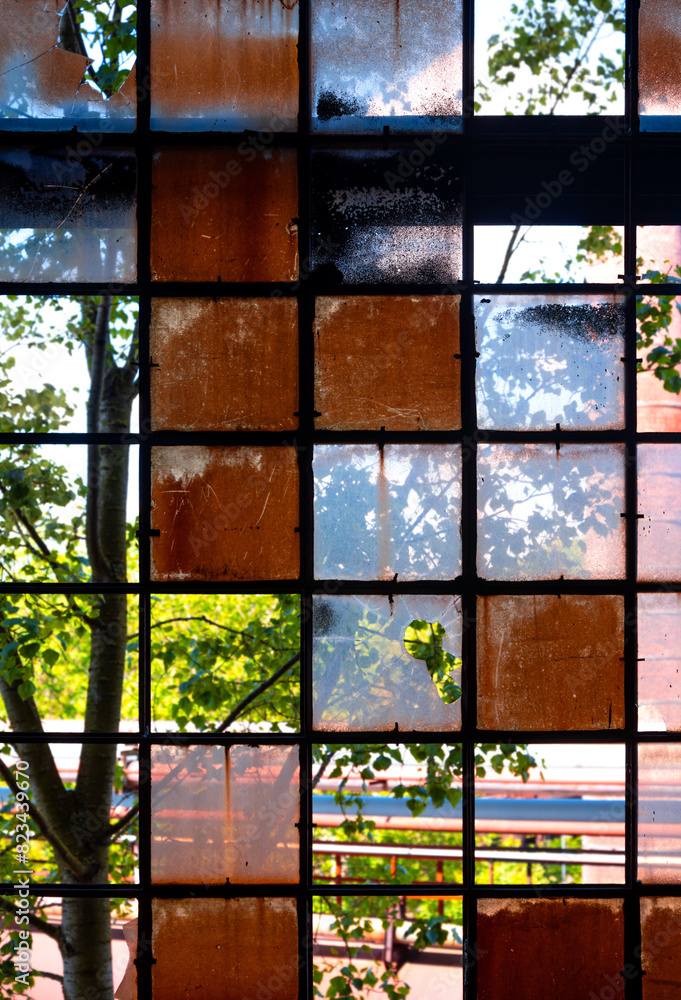 Window of a ruined factory with old brocken glass and rusty iron in in a lost place in Germany. Colorful background with transparent elements of industrial heritage building Völklingen (Saar). Window of a ruined factory with old brocken glass and rusty iron in in a lost place in Germany. Colorful background with transparent elements of industrial heritage building Völklingen (Saar).