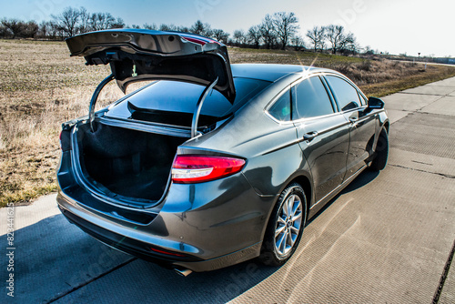 Empty open trunk of a black car with red tail lights