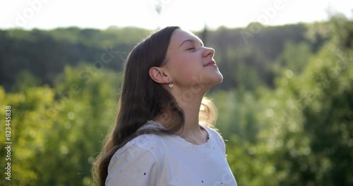 The girl breathes fresh air in nature. Positive mood from good weather and clean environment.