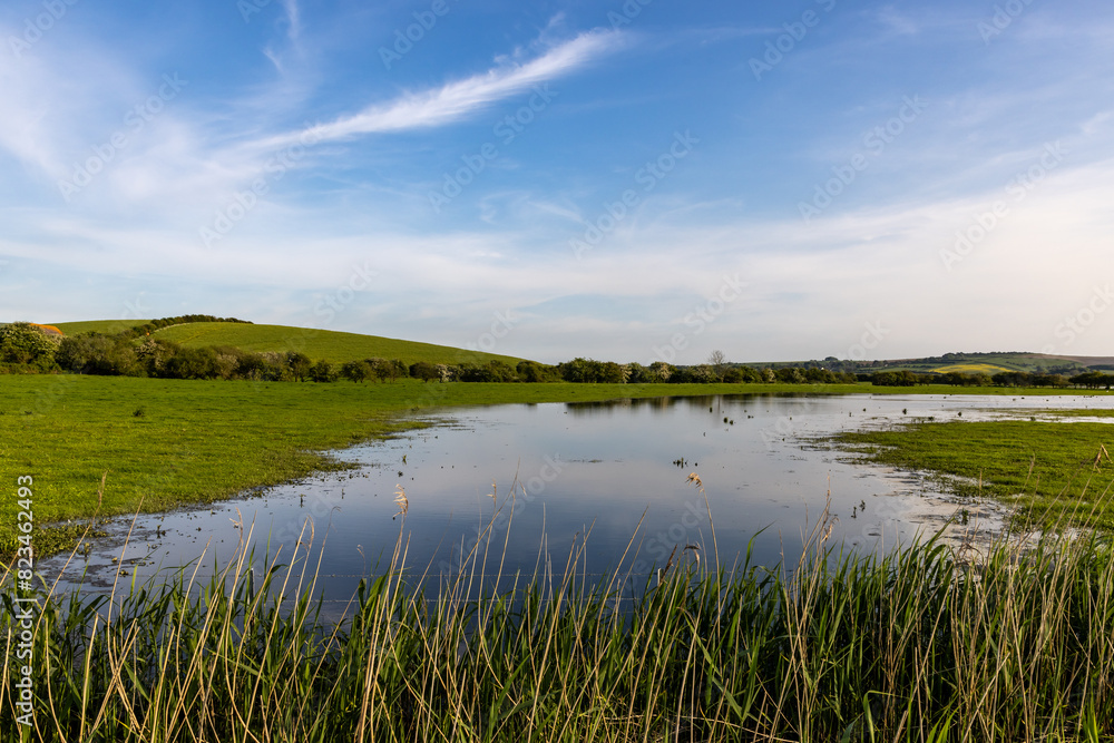 A view over a flooded field in the South Downs, with a blue sky overhead
