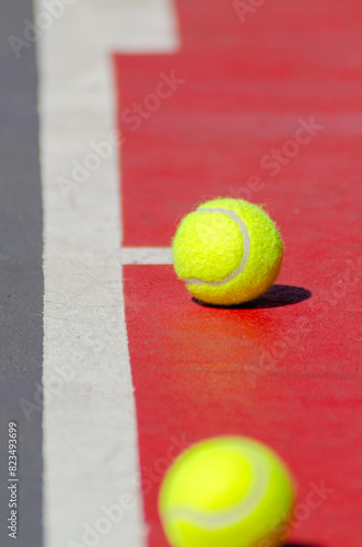two tennis balls next to the line of a tennis court