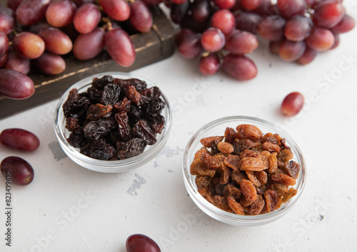 Brown and dark sweet raisins with ripe red grapes on light background.Macro.