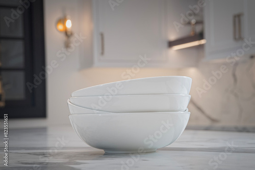 Stack of white bowls sits on a granite counter of a high end kitchen