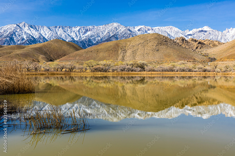 Reflections of The Foothills and Pier With The Sierra Nevada Mountain Range on Diaz Lake, Lone Pine, California, USA