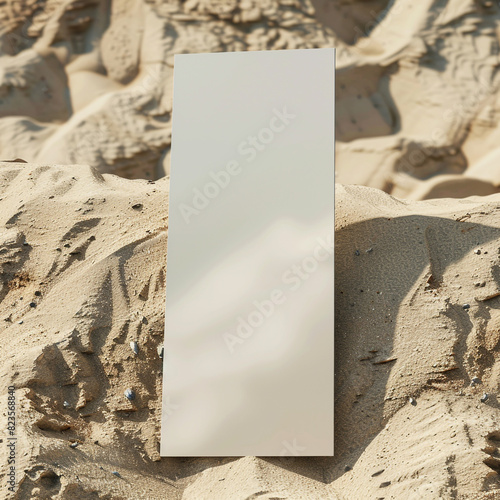 Vertical design of a tall narrow blank business card mockup displayed on a textured sandy beach. photo