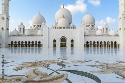 The majestic white marble domes of Abu Dhabi’s iconic mosque against a clear blue sky.
