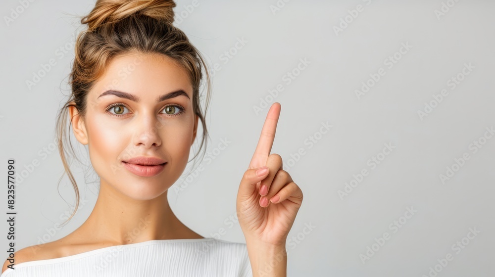 Smiling woman with a bun pointing upwards, white background. Smiling woman with a bun pointing upwards, white background.