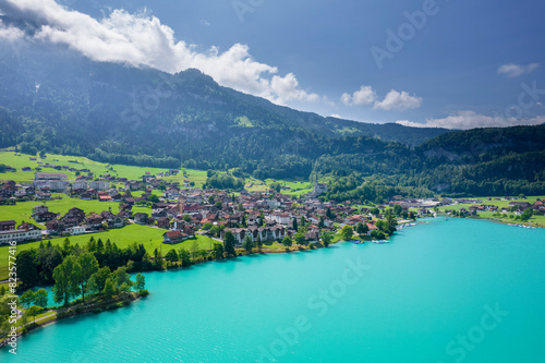 Aerial of Swiss village Lungern with traditional houses  old church Alter Kirchturm along lovely emerald green lake Lungerersee  canton of Obwalden Switzerland