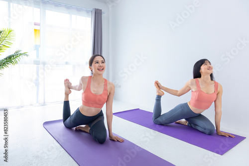 Asian woman friend is practicing yoga indoor with easy and simple leg stretching position to control breathing in and out inside studio class