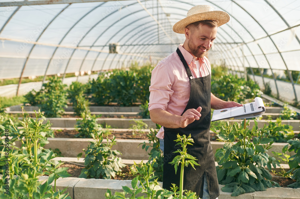 Obraz premium Reading the data. Man in greenhouse is working with plants