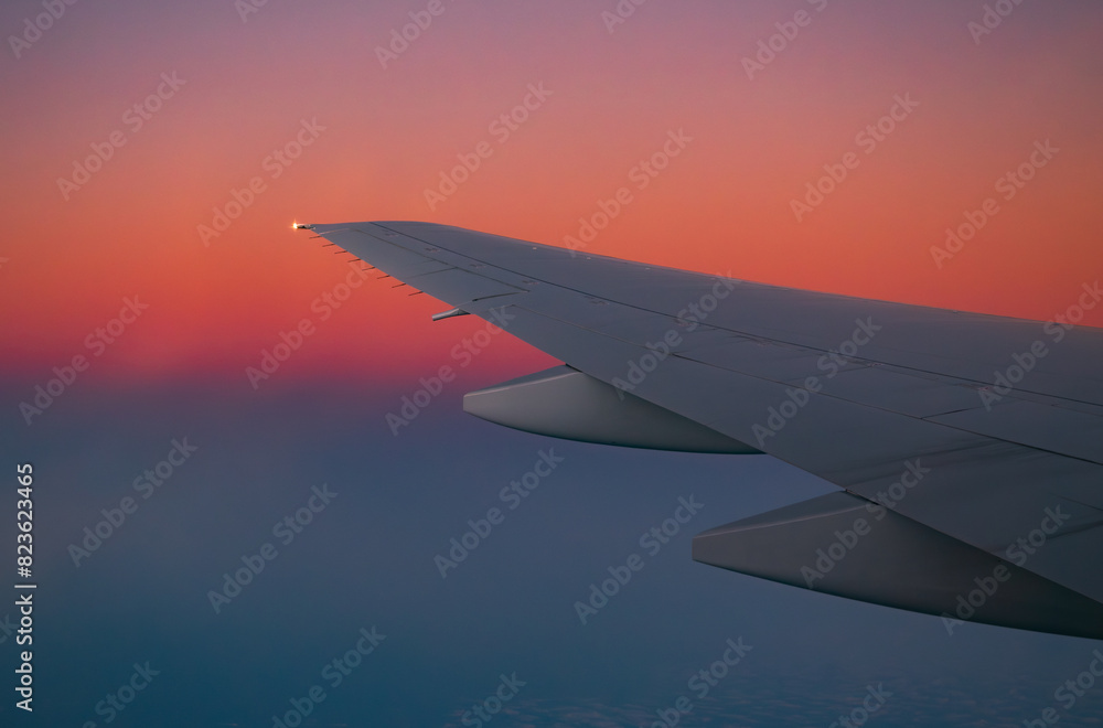 Obraz premium Airplane wing in flight during sunset with vibrant sky