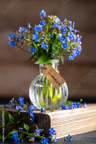 bouquet of blue forget-me-nots in a glass vase. congratulation, beautiful card for birthday, mother's day and wedding