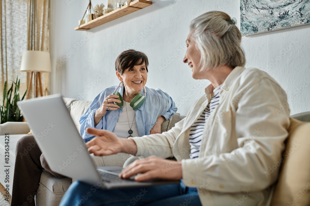 Two women engage in a deep conversation on a laptop while seated on a comfortable couch. Two women engage in a deep conversation on a laptop while seated on a comfortable couch.