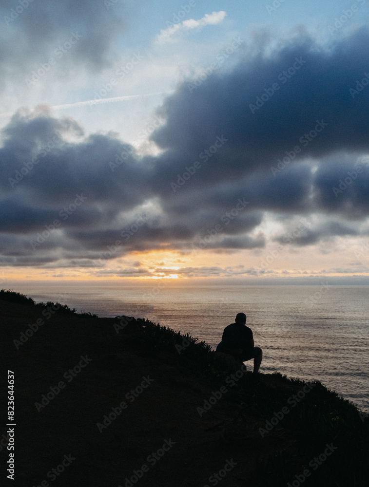 A lone silhouette against a stunning sunset over the ocean, evoking peace and reflection