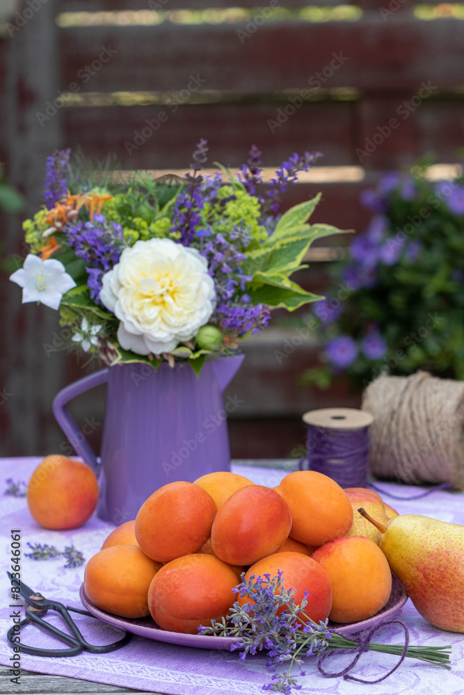 Tischdekoration mit frischen Aprikosen und Sommerblumenstrauß in Weiß und Lila Tischdekoration mit frischen Aprikosen und Sommerblumenstrauß in Weiß und Lila