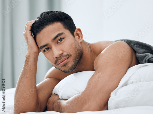 Morning, portrait and Asian man lying in bed with confidence for relax, wellness and wakeup in bedroom. Home, body and male person with muscles for resting, comfortable or weekend break in apartment