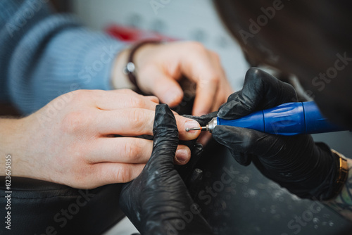 Professional manicurist using electric tool in modern salon  carefully polishing clients nails. Expertise in nail art  attention to detail  and dedication to hand care