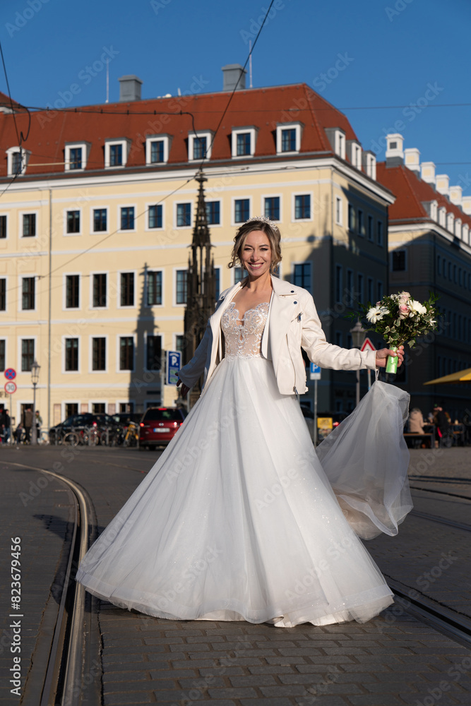 A happy bride with a bouquet in her hands walks along a city street. View from below. Dresden, Germany A happy bride with a bouquet in her hands walks along a city street. View from below. Dresden, Germany