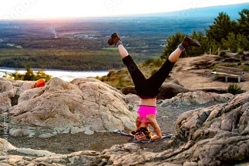 Young girl practicing yoga stand at the mountain top at sunset