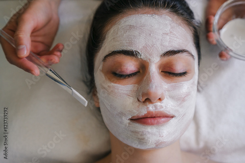 Fotografija A woman is having a white mask applied to her face