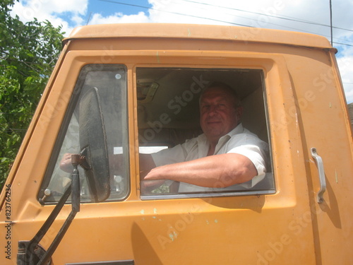 an elderly man sits in a truck behind the wheel