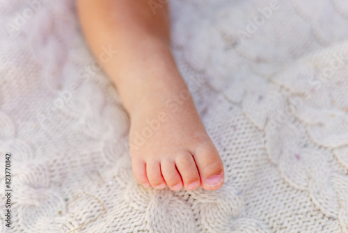 the leg of a small child of six months on a beige bedspread, space for text, baby's leg.