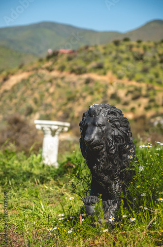 Majestic guardian: a striking black lion sculpture amidst white daisies and lush green grass