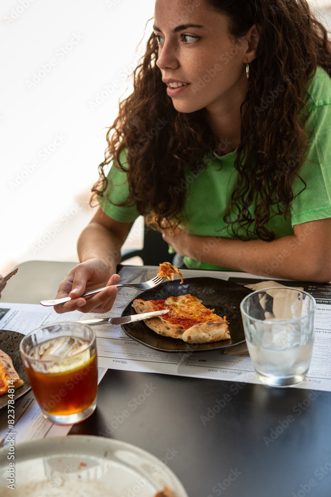 A young woman eating pizza at a restaurant A young woman eating pizza at a restaurant
