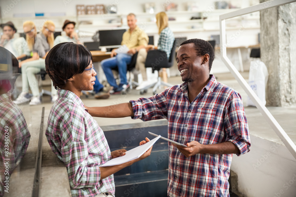 Two African American colleagues discussing paperwork in a creative office space Two African American colleagues discussing paperwork in a creative office space