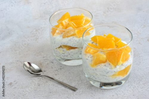 two glasses of chia pudding with orange and spoon on a table