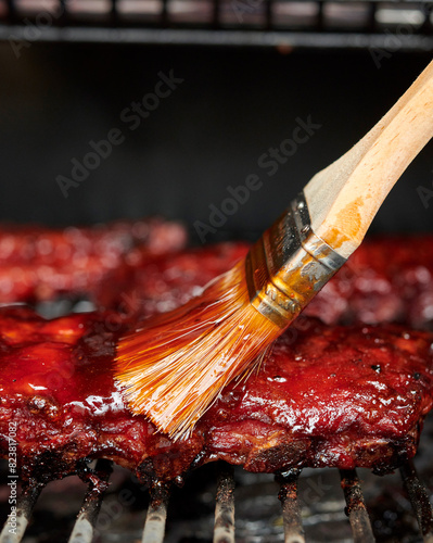 Ribs on a grill being brushed with sauce. photo