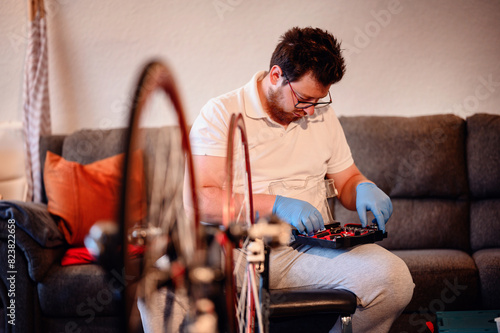 A mechanic wearing blue gloves organizing tools in a workshop, with a bicycle wheel in the foreground.