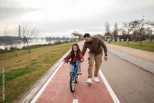 father teaching his daughter to ride a bicycle