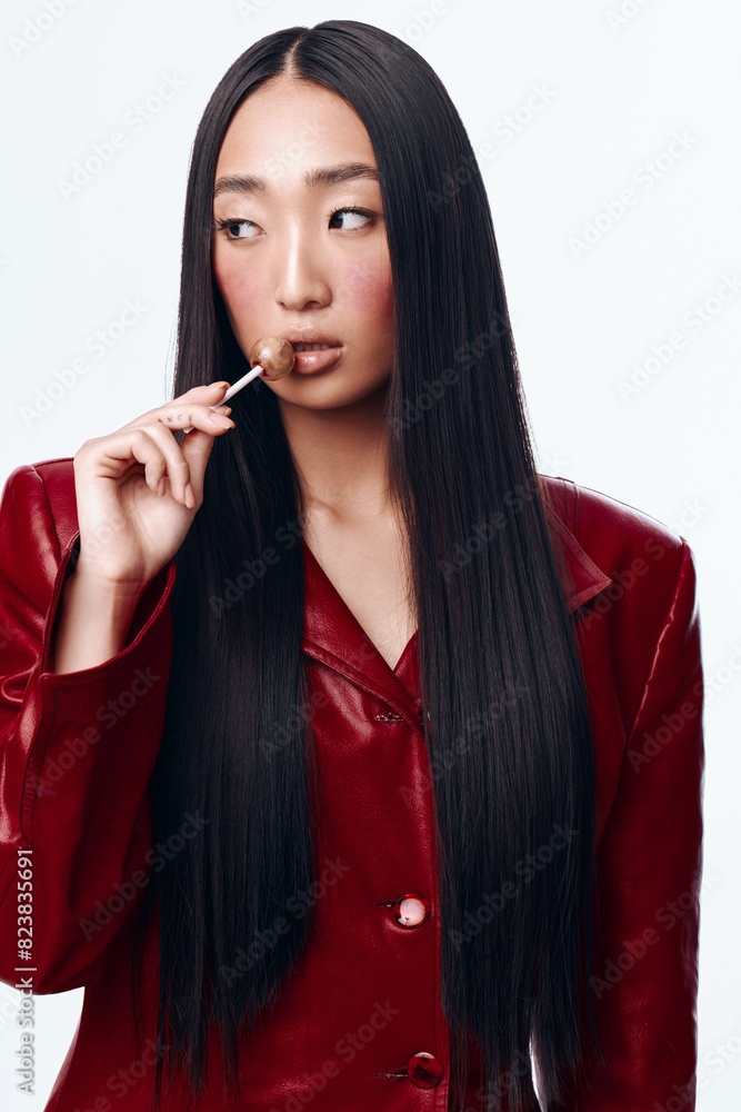 Young Asian woman with long black hair and red jacket smoking a cigarette outdoors Young Asian woman with long black hair and red jacket smoking a cigarette outdoors