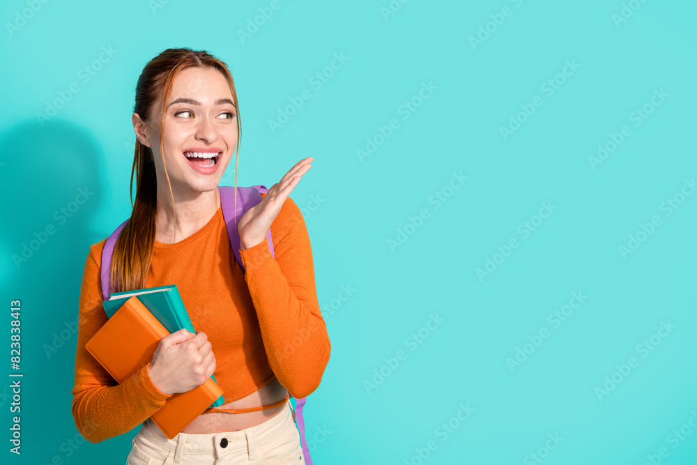 Portrait of overjoyed woman wear orange crop top rucksack hold book look at discount empty space isolated on turquoise color background Portrait of overjoyed woman wear orange crop top rucksack hold book look at discount empty space isolated on turquoise color background