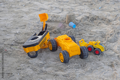 Yellow Construction Equipment Toys in Sand at Beach photo