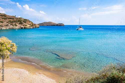 Secluded sandy beach and catamaran boat in sea bay near Chrysopigi monastery, Sifnos island, Greece