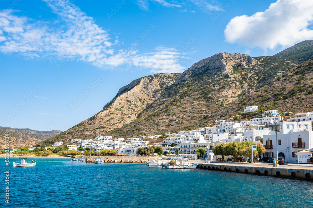 View of Kamares port and village with white houses on hill in mountain landscape, Sifnos island, Greece